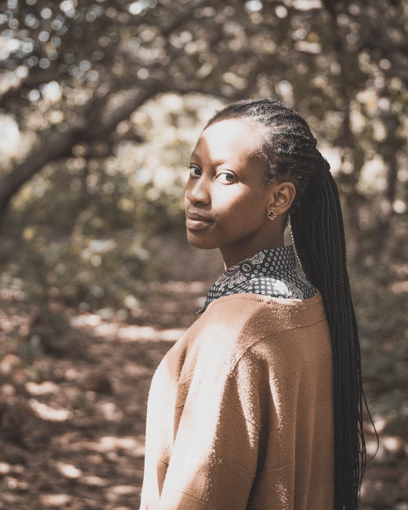A woman gracefully poses in a serene Nigerian forest, showcasing natural beauty.